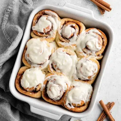 soft homemade cinnamon rolls with cream cheese icing in white dish
