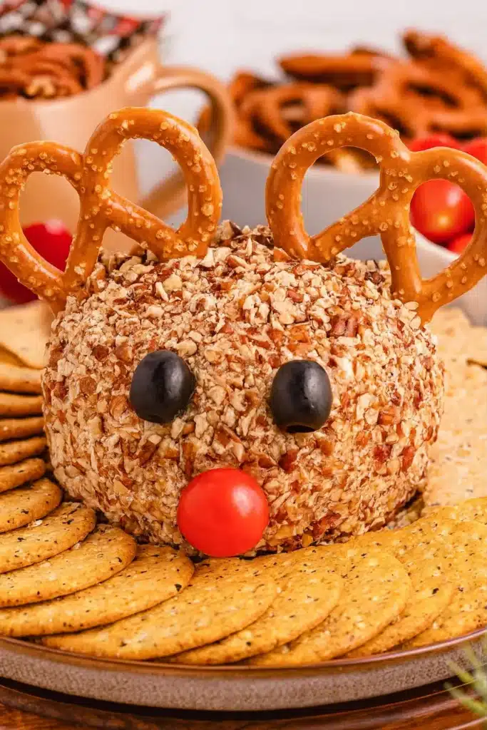 Reindeer cheese ball with pretzel antlers and crackers on holiday platter