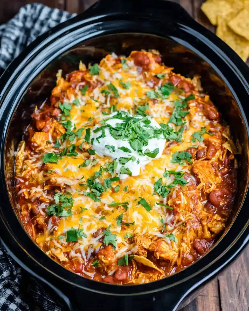 Delicious crockpot chicken enchilada casserole in a black slow cooker.