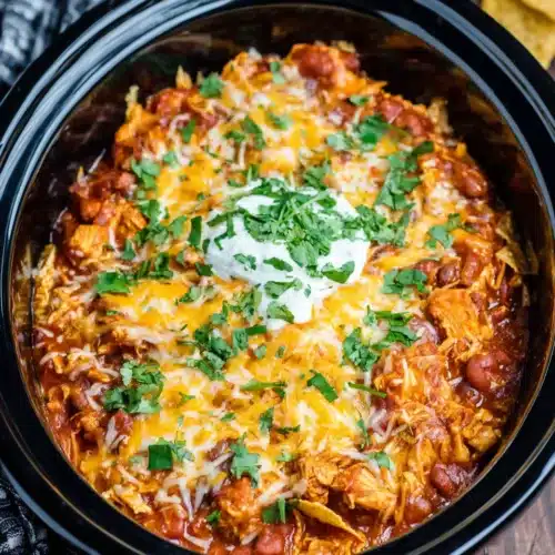 Delicious crockpot chicken enchilada casserole in a black slow cooker.