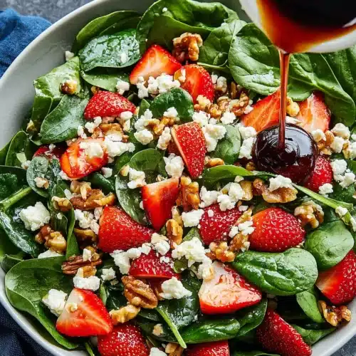 Spinach strawberry salad with balsamic dressing featuring fresh ingredients and vibrant colors.