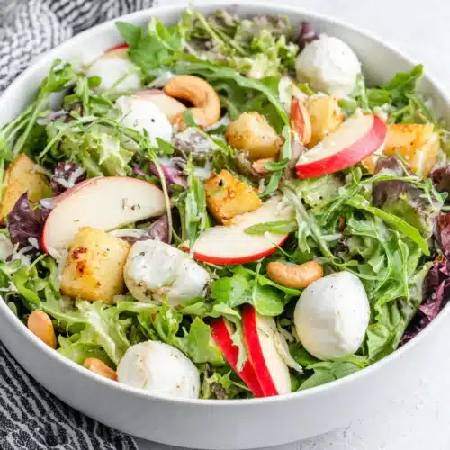 A vibrant spring salad with apples, greens, mozzarella, and cashews.
