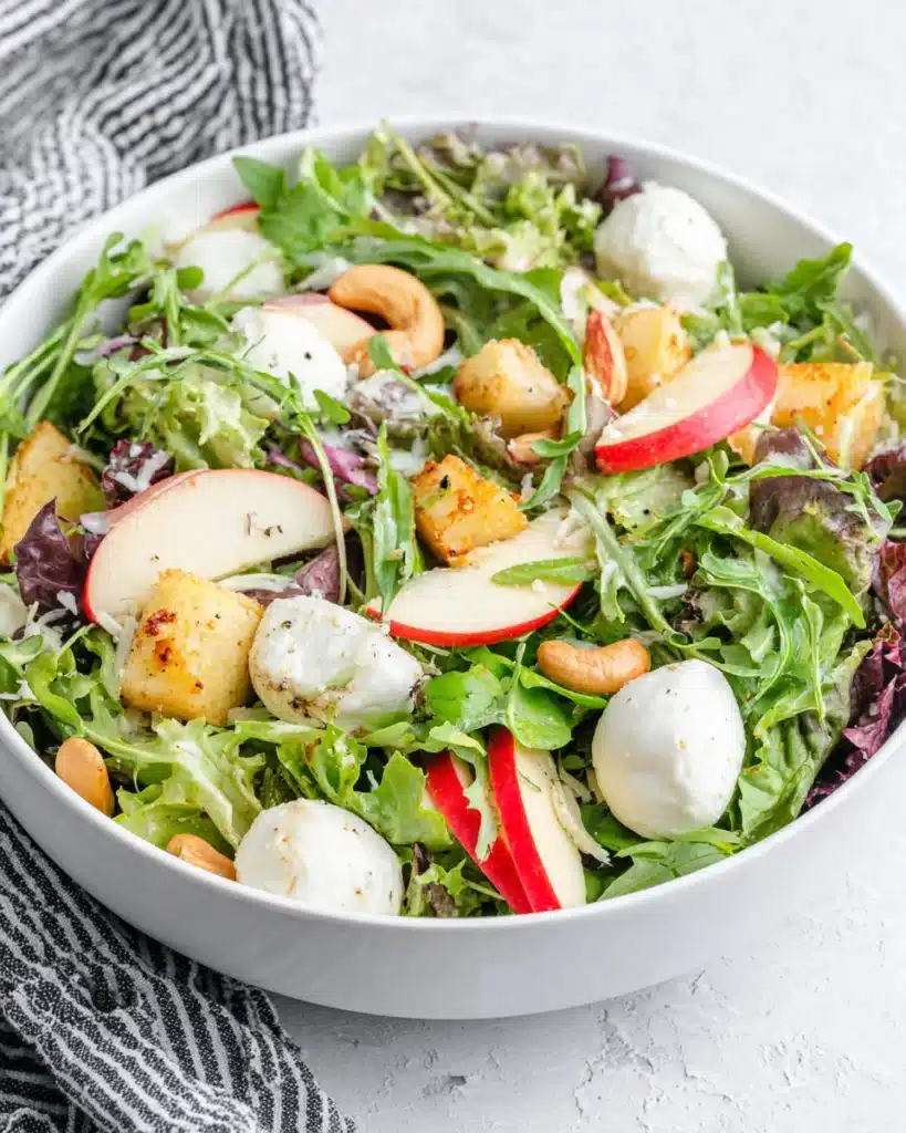 A vibrant spring salad with apples, greens, mozzarella, and cashews.