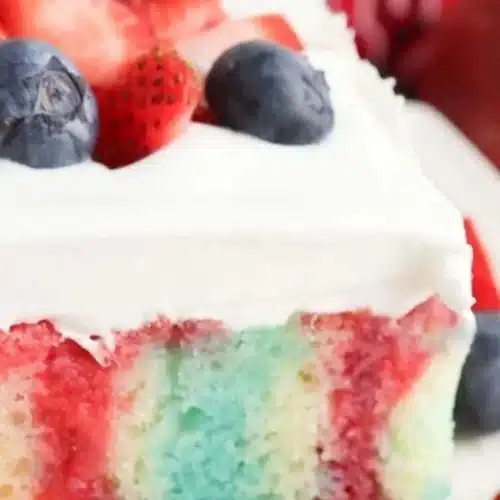 Delicious Berry Poke Cake topped with fresh berries and whipped cream