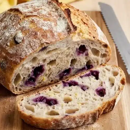 Sliced Blueberry Lemon Sourdough Bread on a wooden board with fresh blueberries.