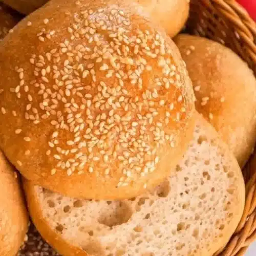 Freshly baked gluten-free sourdough hamburger buns on a wooden table