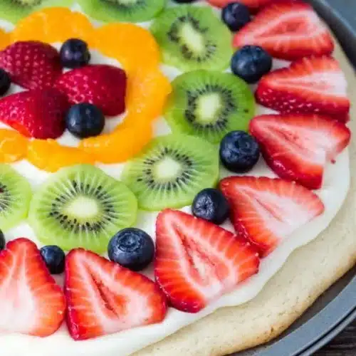Colorful sugar cookie fruit pizza topped with fresh fruits and cream